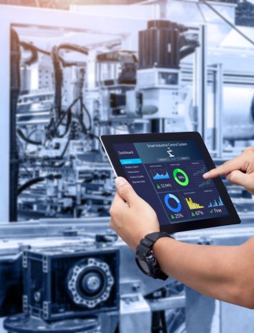 Hands holding tablet on blurred automation machine as background